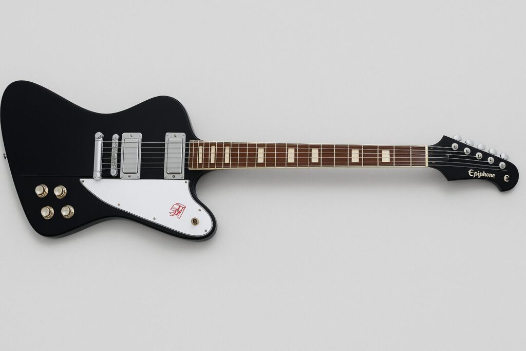 Epiphone「Inspired by Gibson Custom 1963 Firebird V」モデルのデジタル画像。ブラックフィニッシュのリバースボディ、ミニハムバッカーピックアップ2基、トラペゾイドインレイ付きローズウッド指板、白いピックガードに赤いファイヤーバードロゴが描かれている。